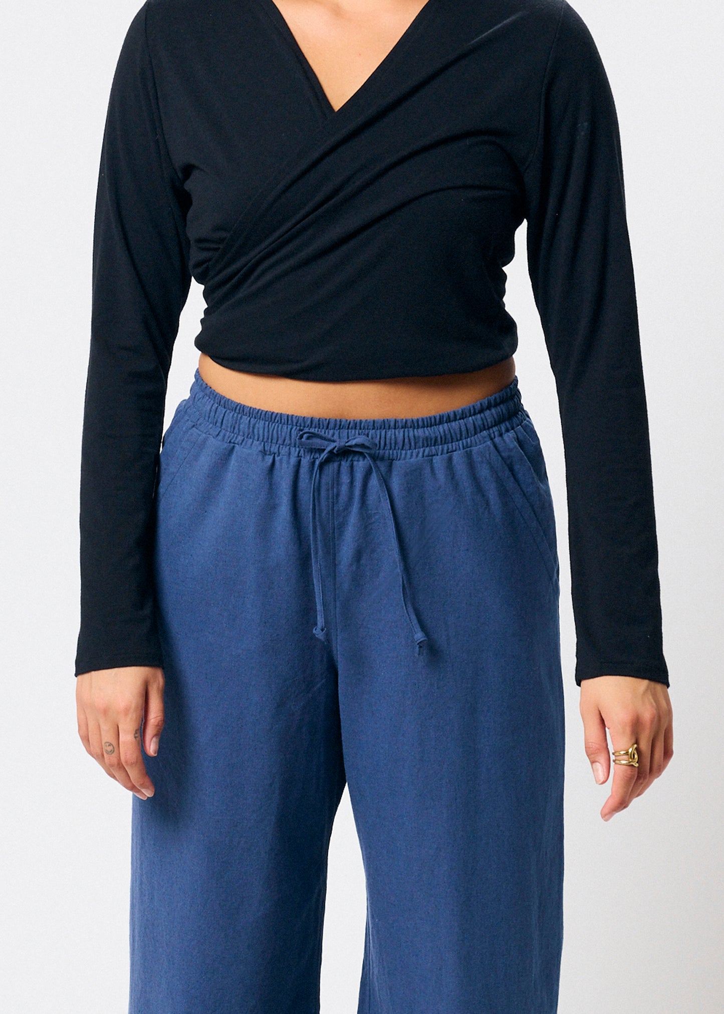 Person wearing a black long-sleeve top and blue pants on a white background