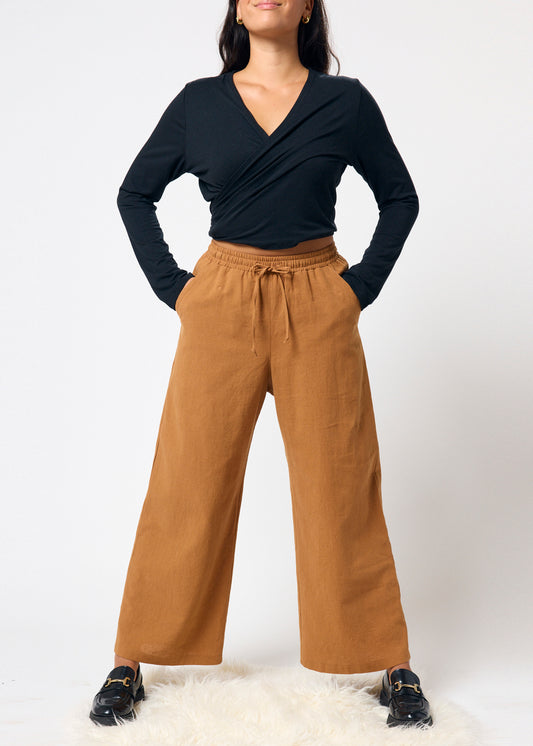 Woman wearing a black top and brown pants on a white background