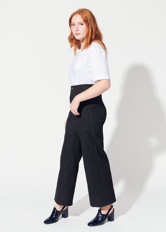 Woman wearing a white top and black pants against a white background