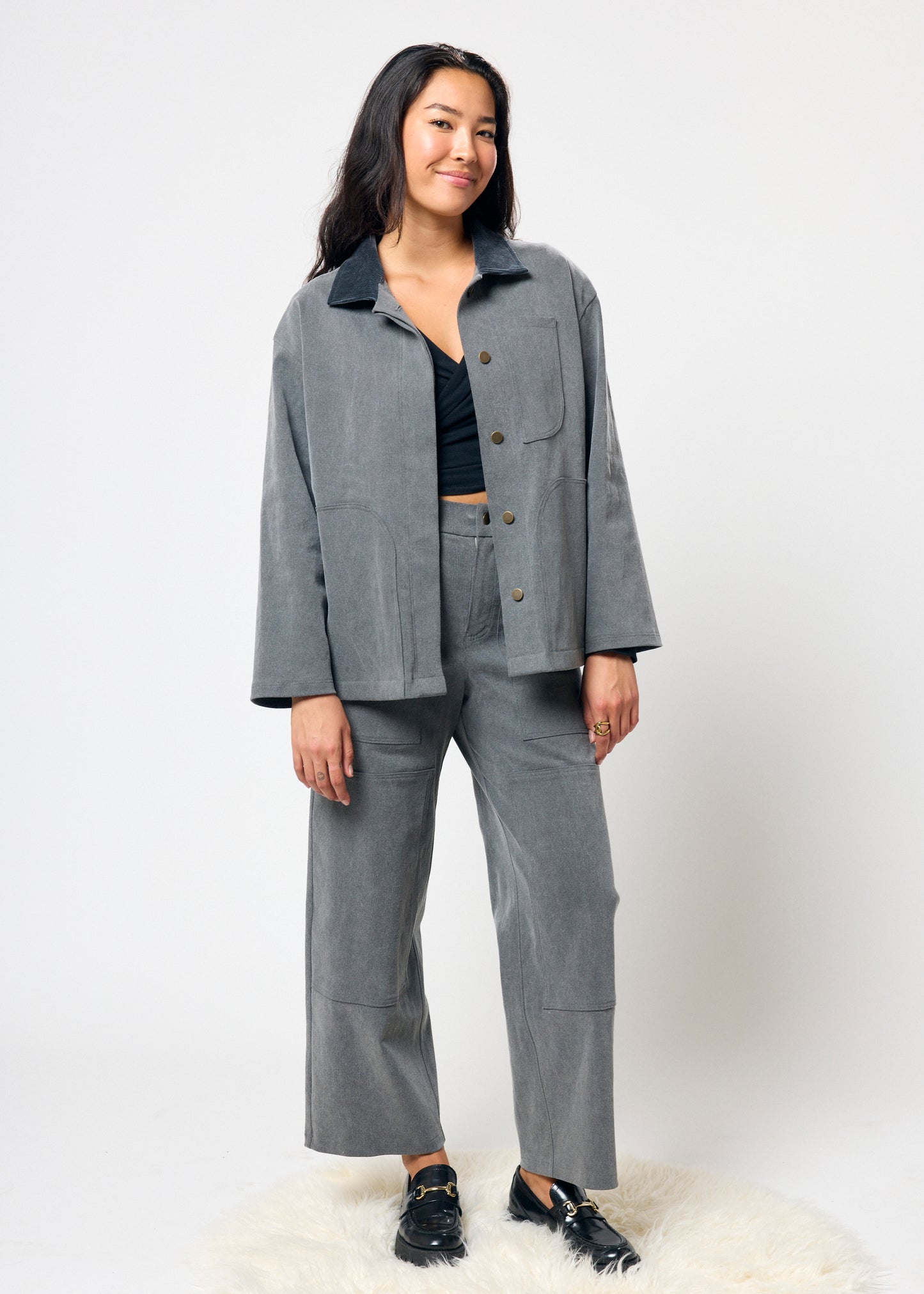 Person wearing a gray outfit with a jacket and pants on a white background