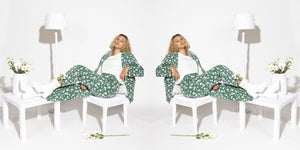 banner featuring woman wearing green flower suit sitting on chair