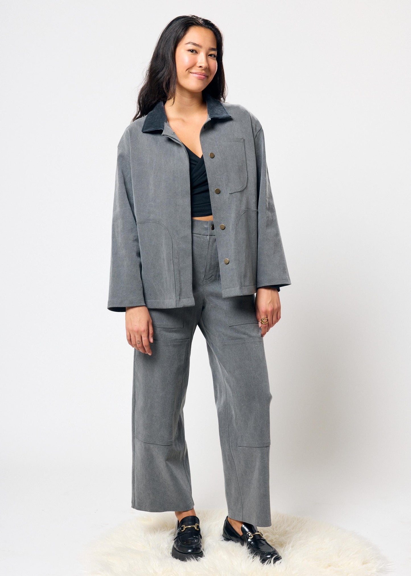 Woman wearing a gray outfit with a jacket and pants on a white background