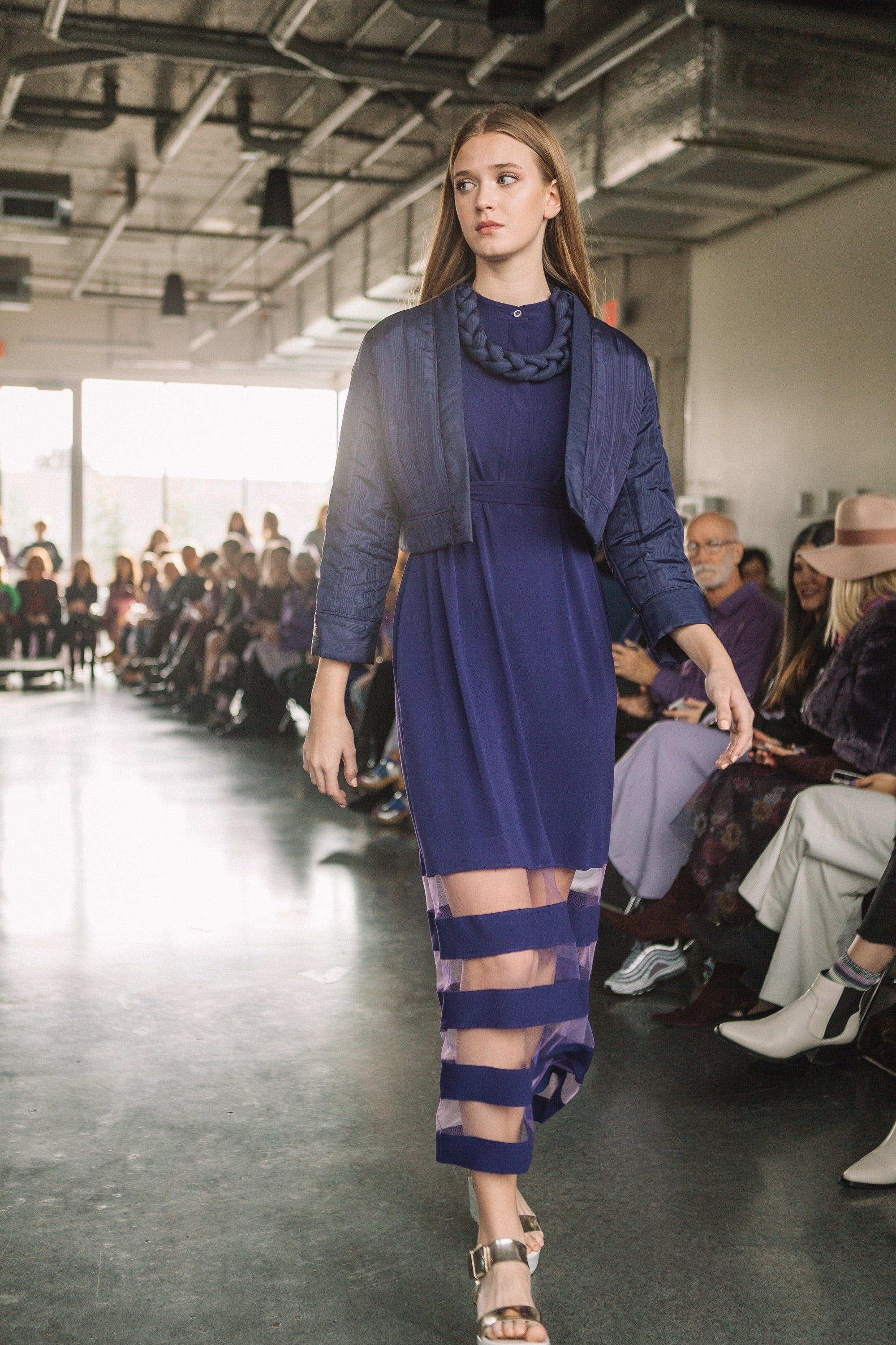 Model wearing a purple dress with cut-out design on a runway