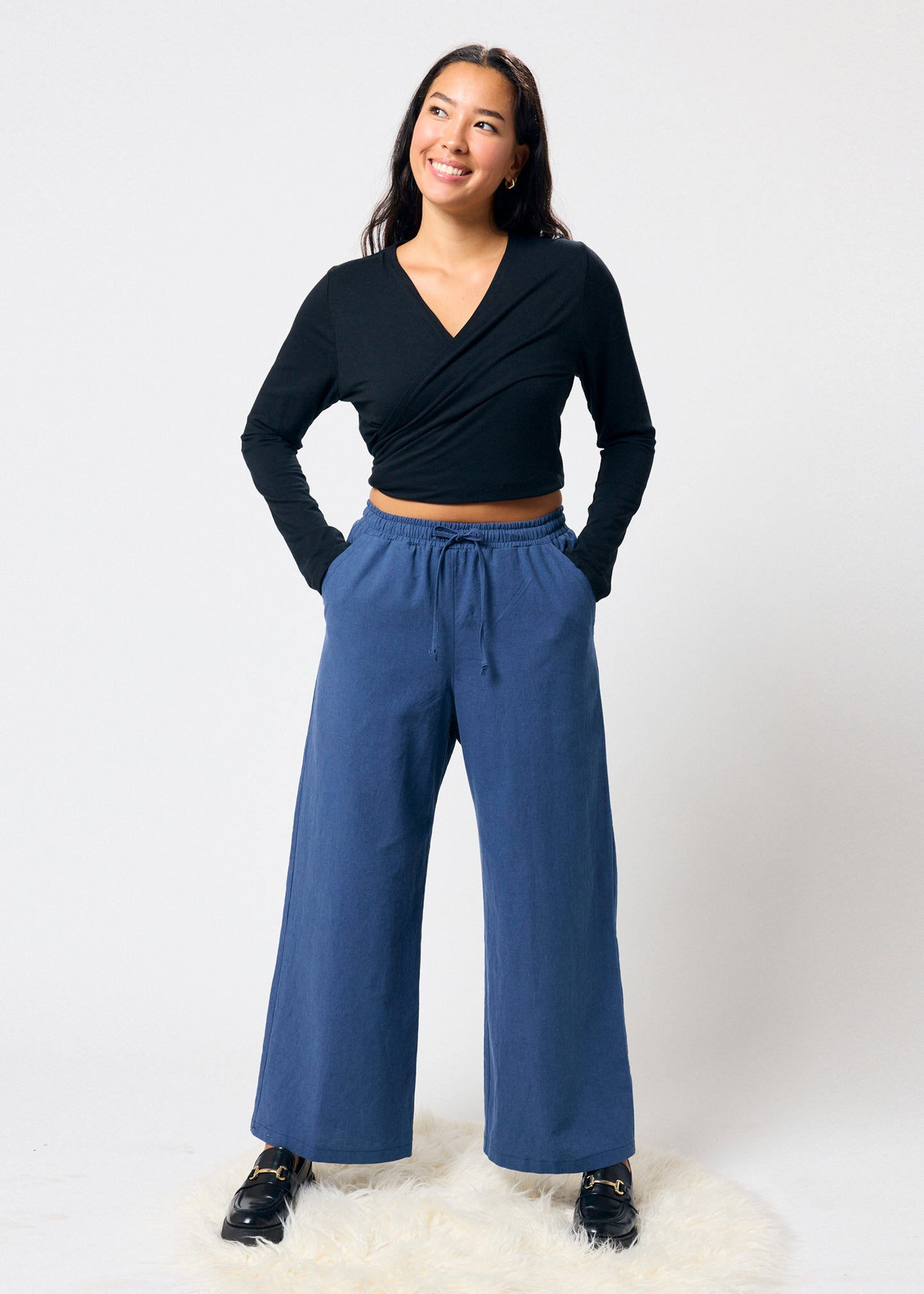 Woman wearing a black top and blue pants on a white background