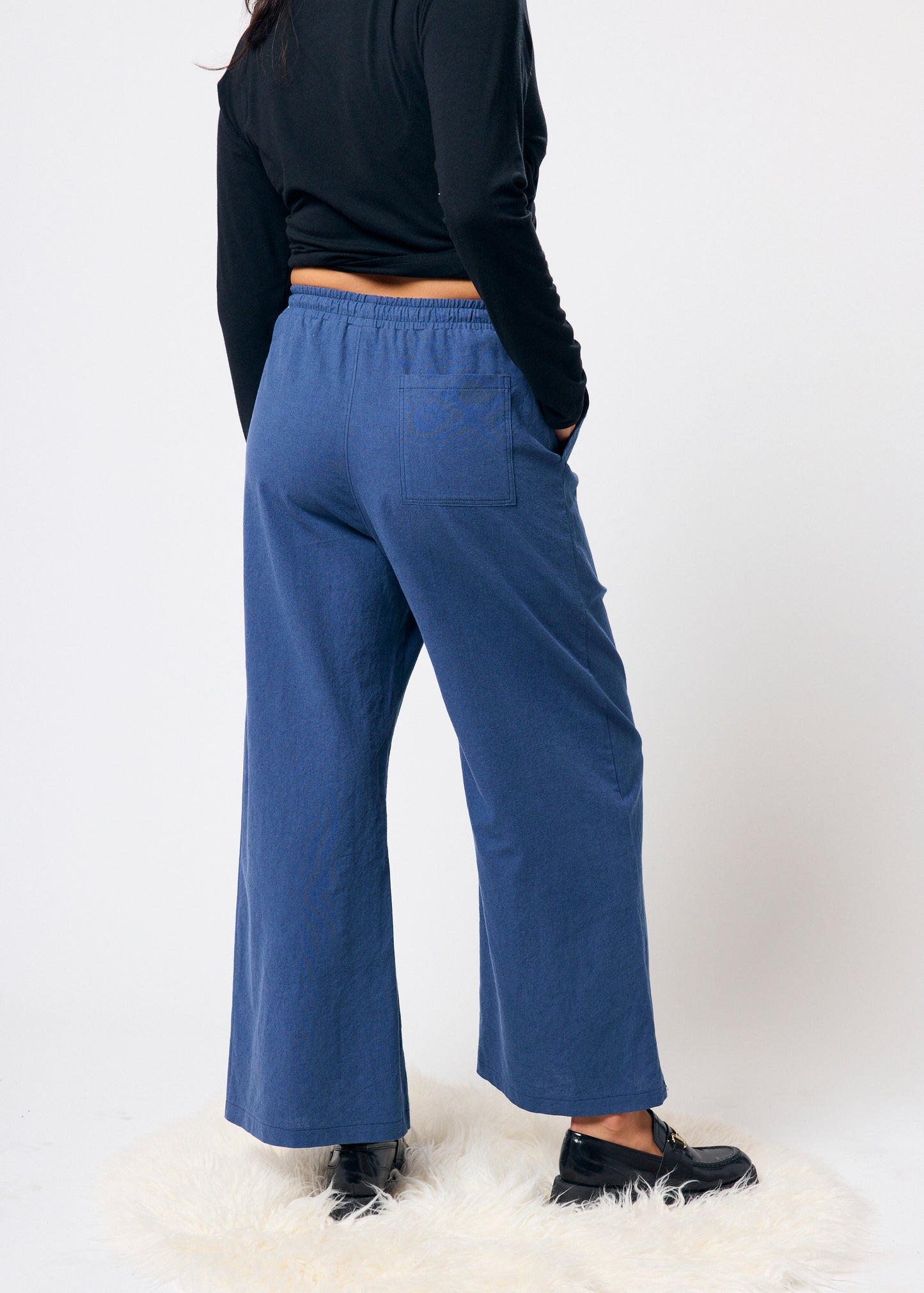 Person wearing blue pants and a black top on a white background