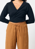 Person wearing a black long-sleeve top and brown pants on a white background
