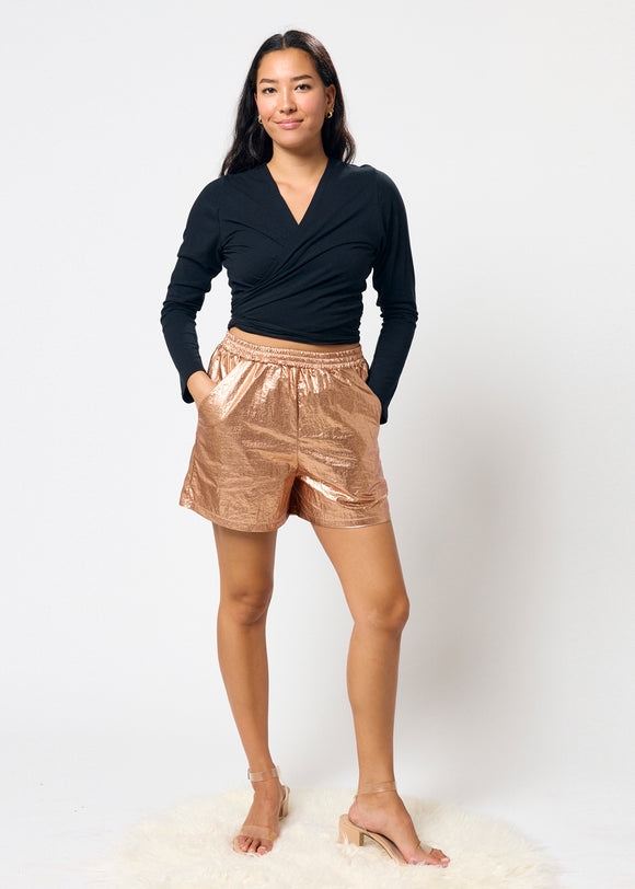 Woman wearing a black top and bronze shorts on a white background