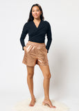 Woman wearing a black top and bronze shorts on a white background