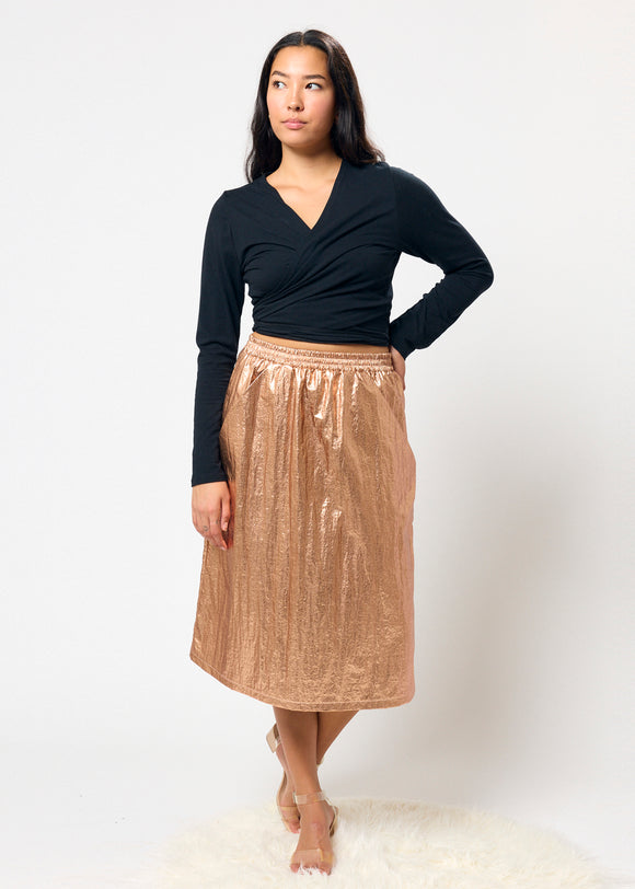 Woman wearing a black top and bronze skirt on a white background