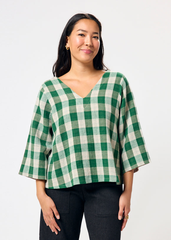 Woman wearing a green and white checkered blouse against a white background