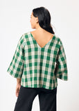 Woman wearing a green and white checkered top on a white background