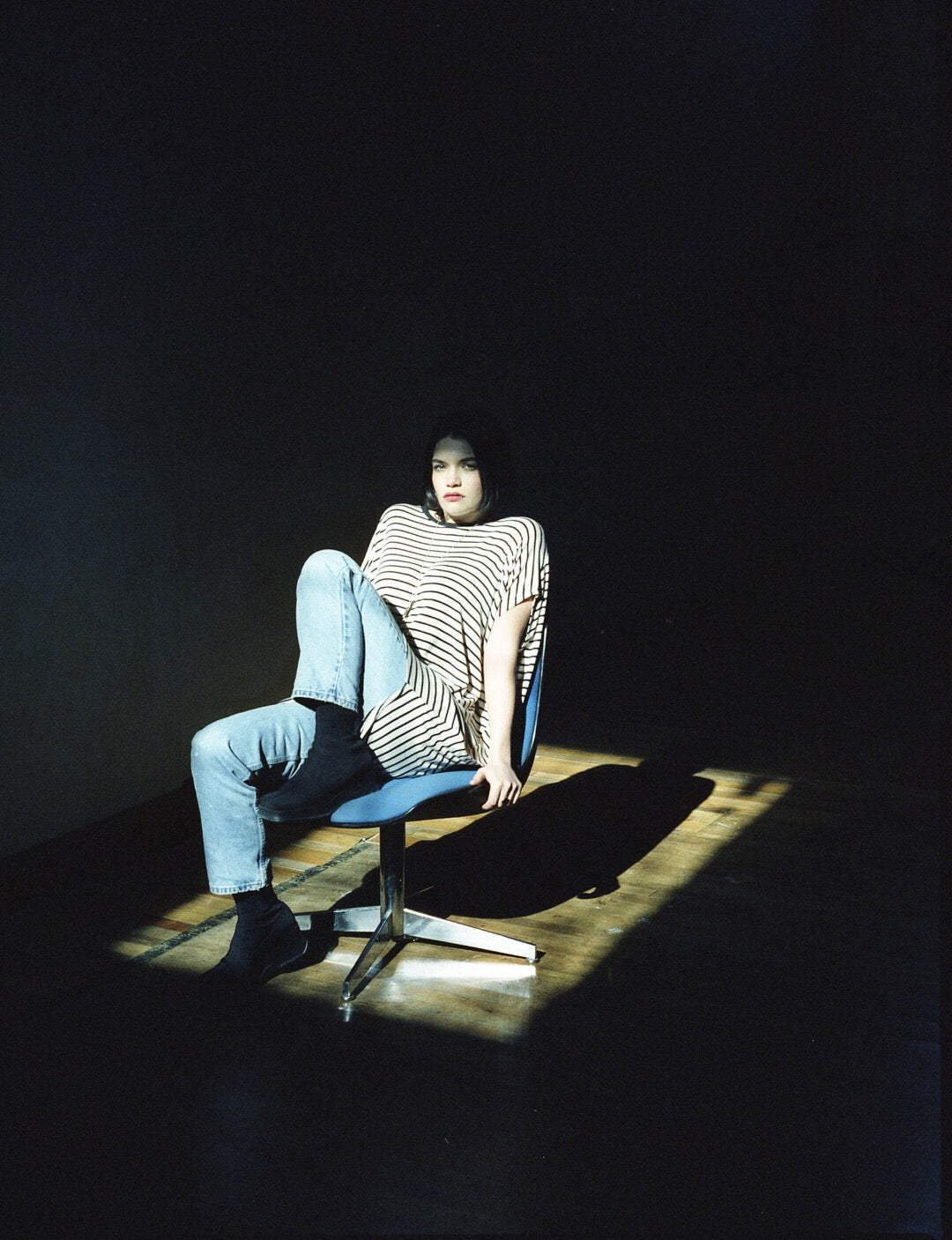 Person sitting on a chair in a dark room with a spotlight