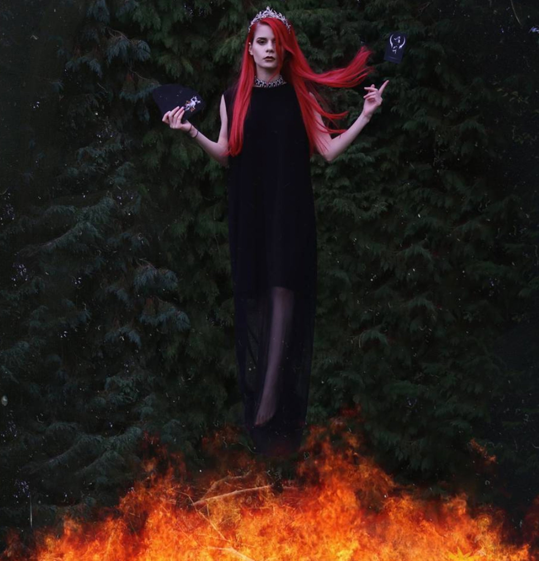 Woman with red hair standing over flames against a dark background