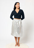 Woman wearing a black top and silver skirt on a white background