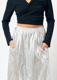 Person wearing black shirt and silver metallic skirt