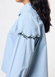 Light blue shirt with barbed wire design on a plain background