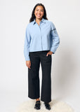 Person wearing a light blue shirt and black pants on a white background
