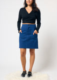Person wearing a black top and blue skirt on a white background
