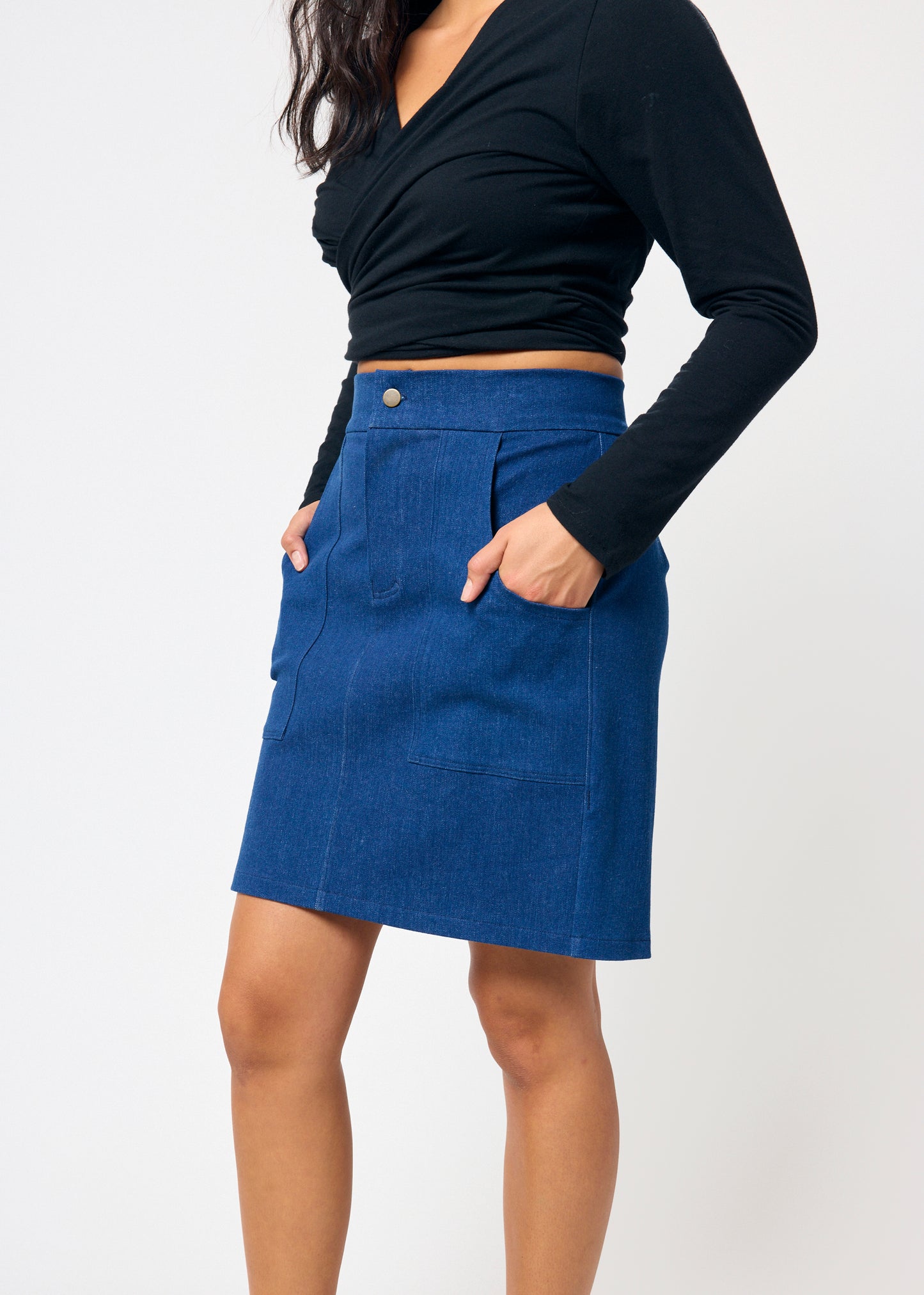 Person wearing a blue skirt and black long-sleeve top on a white background
