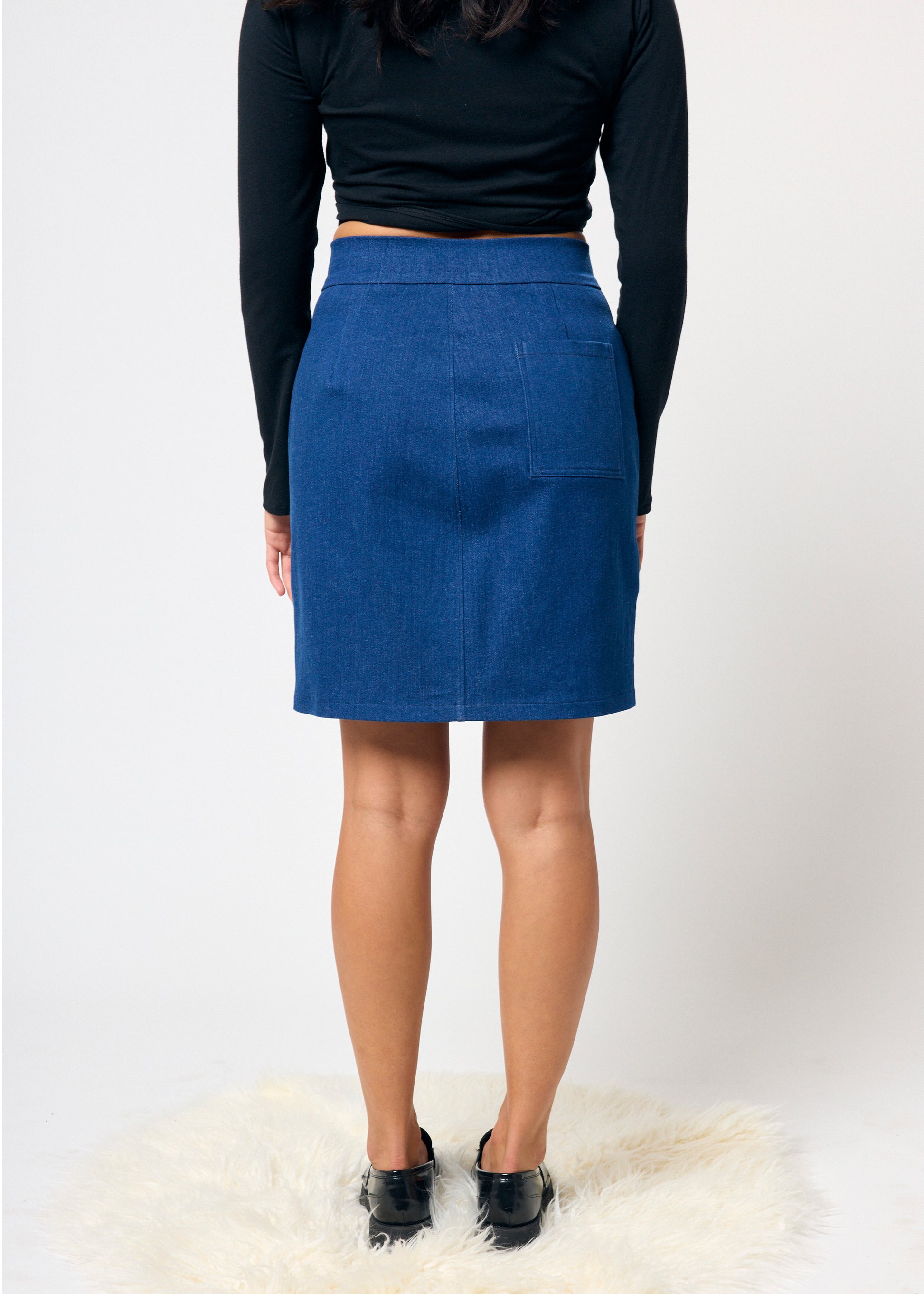 Person wearing a blue skirt and black top on a white background