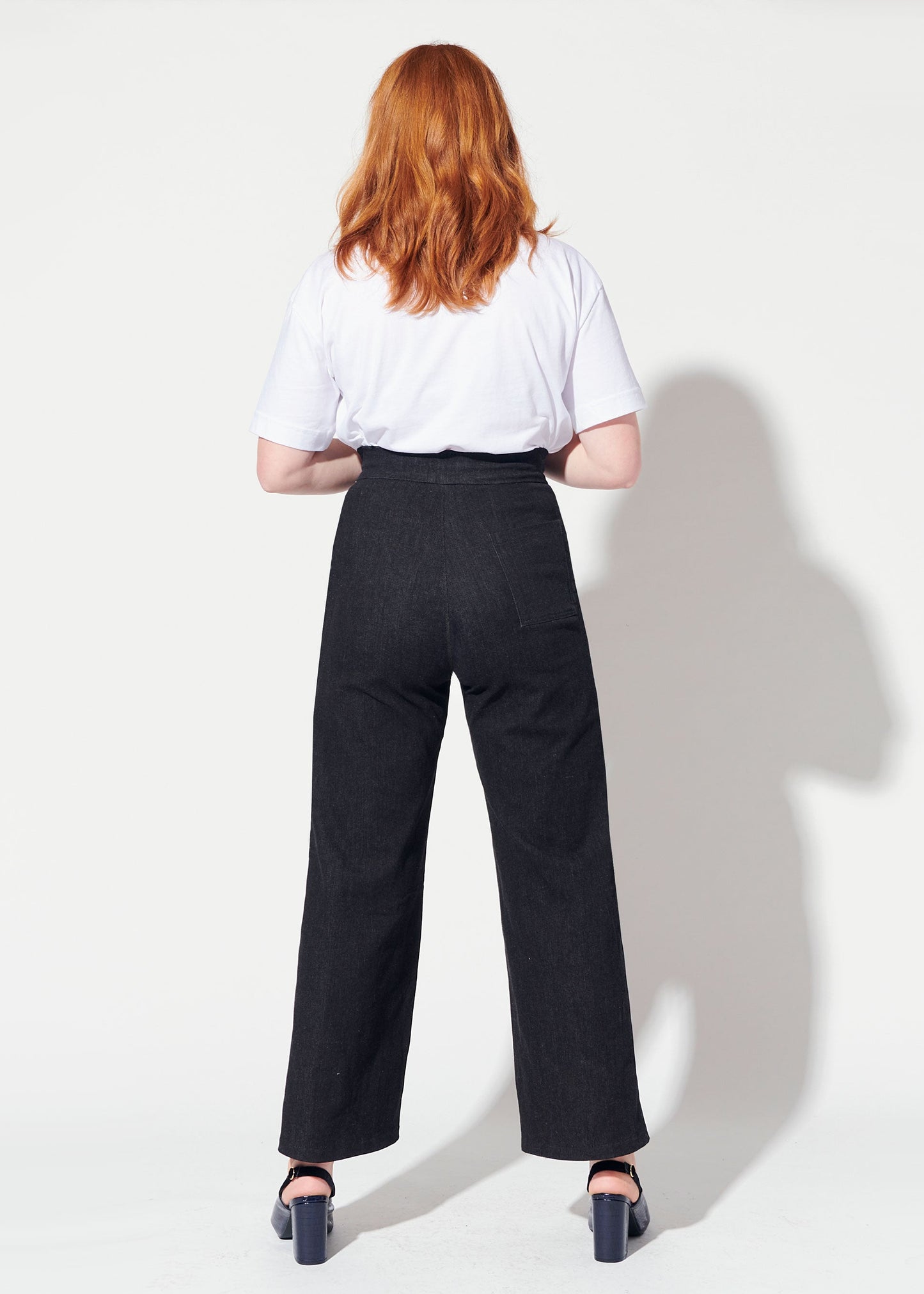 Person wearing a white shirt and black pants against a white background