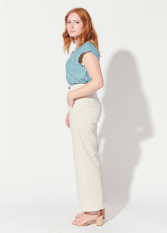 Woman wearing a blue top and white pants against a white background