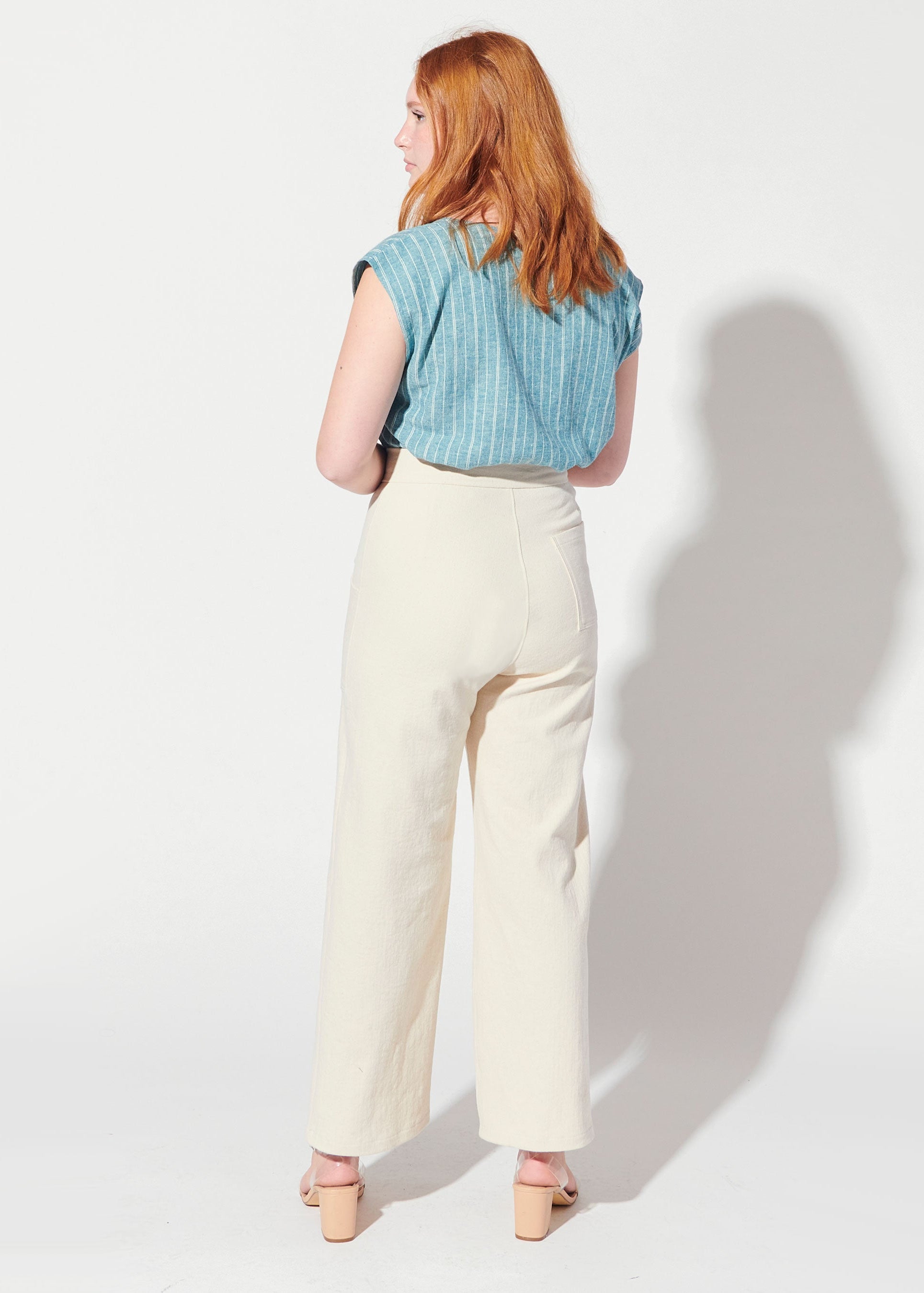 Person wearing a blue striped shirt and beige pants on a white background