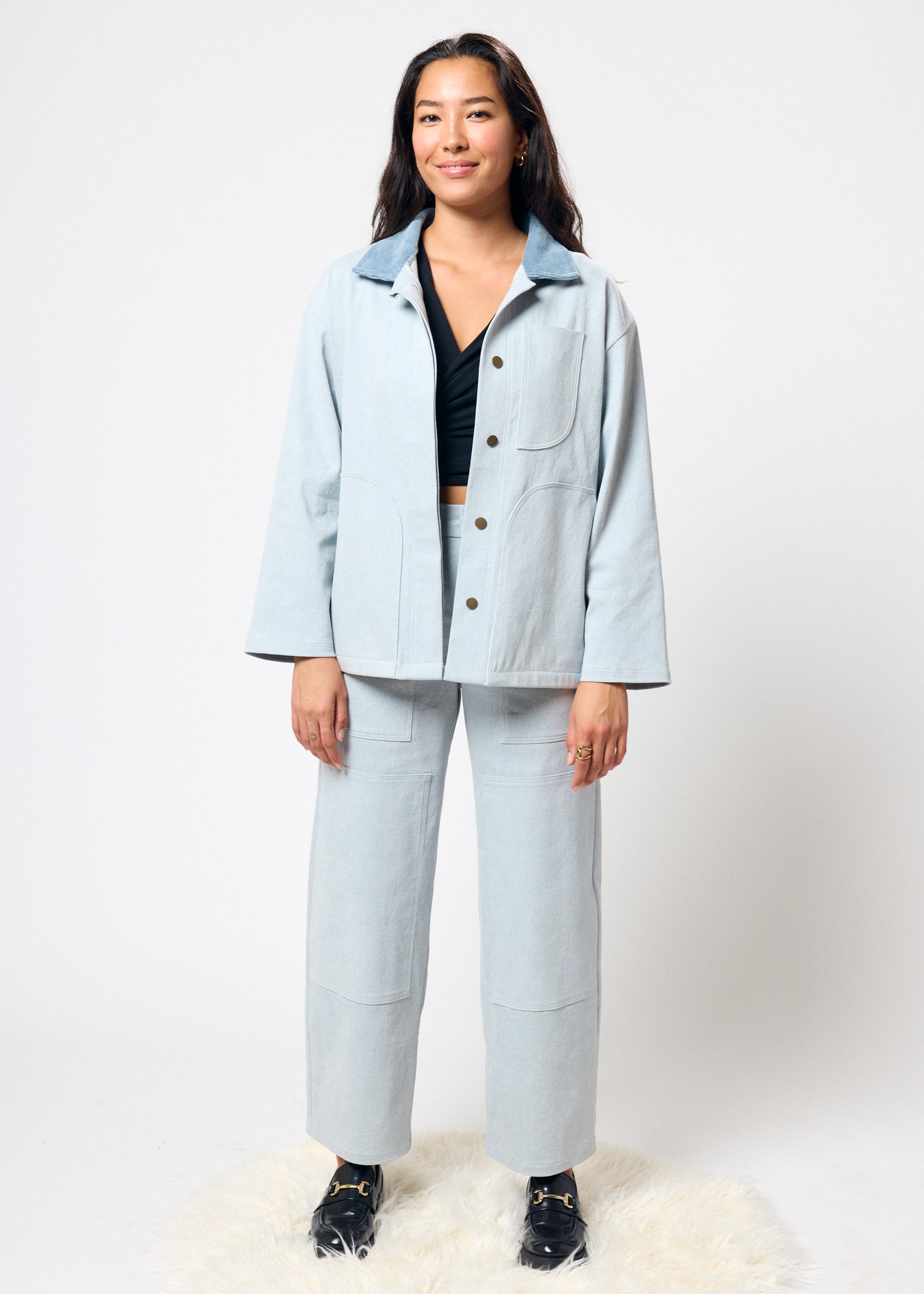 Person wearing a light blue jacket and pants on a white background