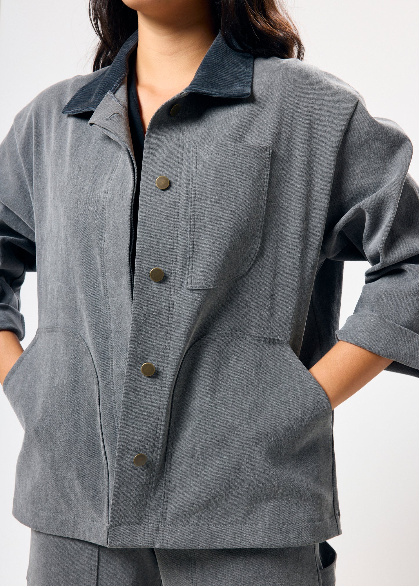 Person wearing a gray jacket with button details on a white background