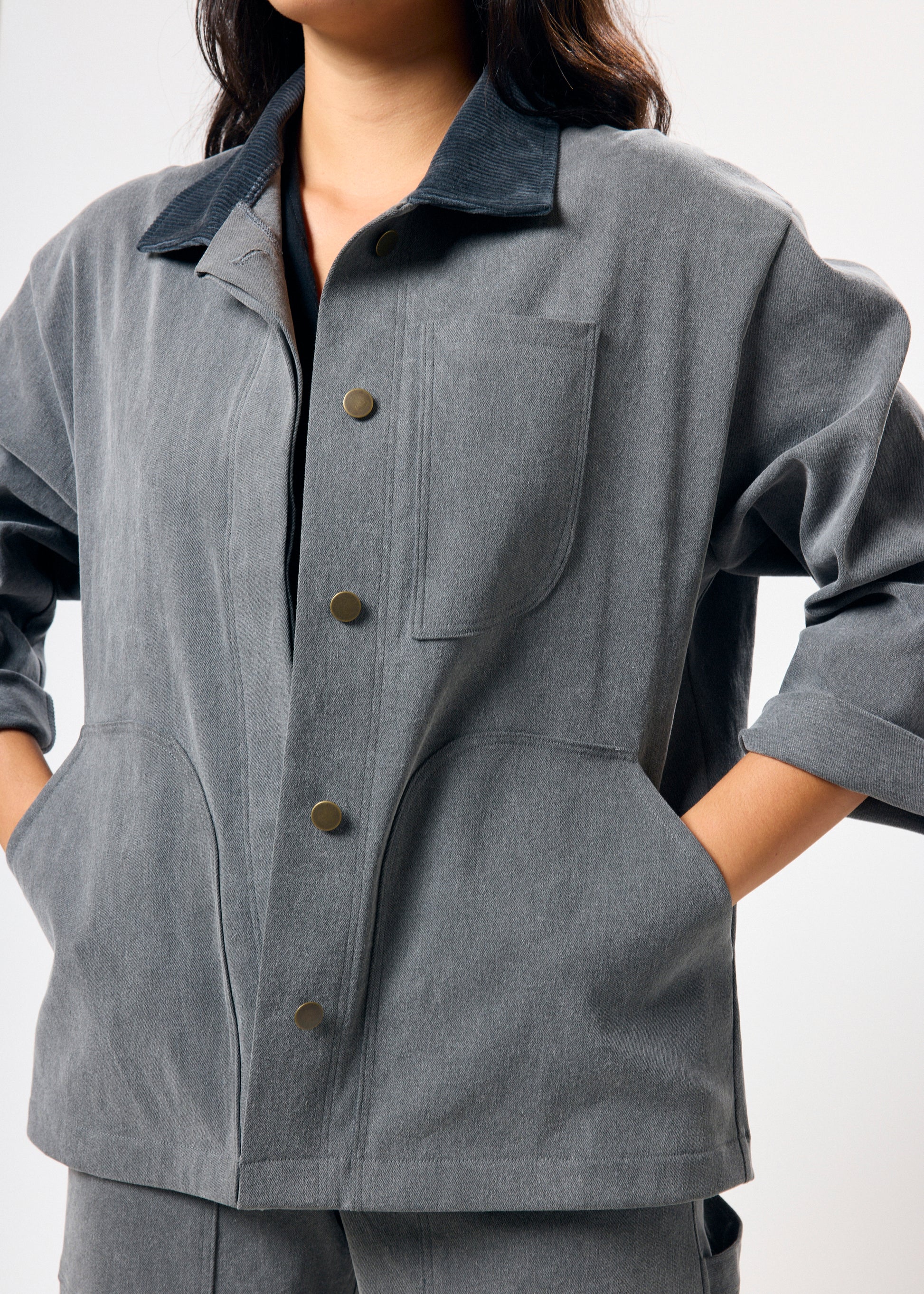 Person wearing a gray jacket with button details on a white background