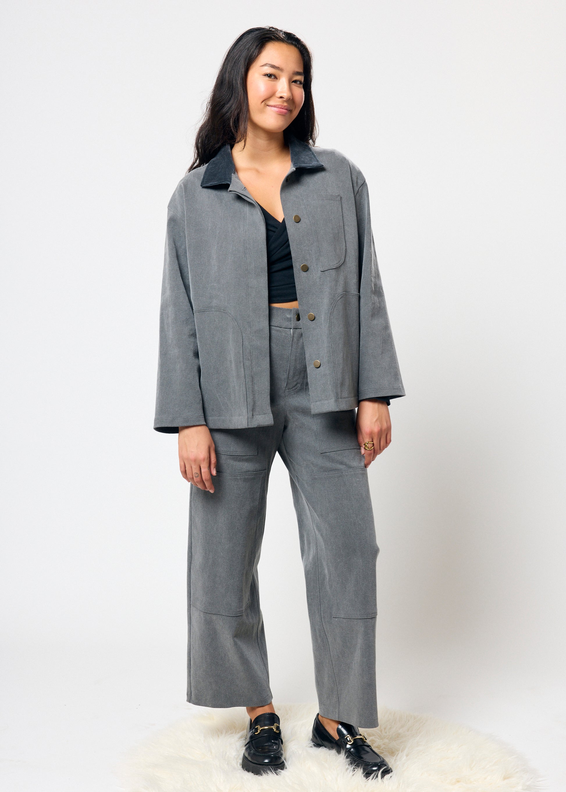 Person wearing a gray outfit with a jacket and pants on a white background
