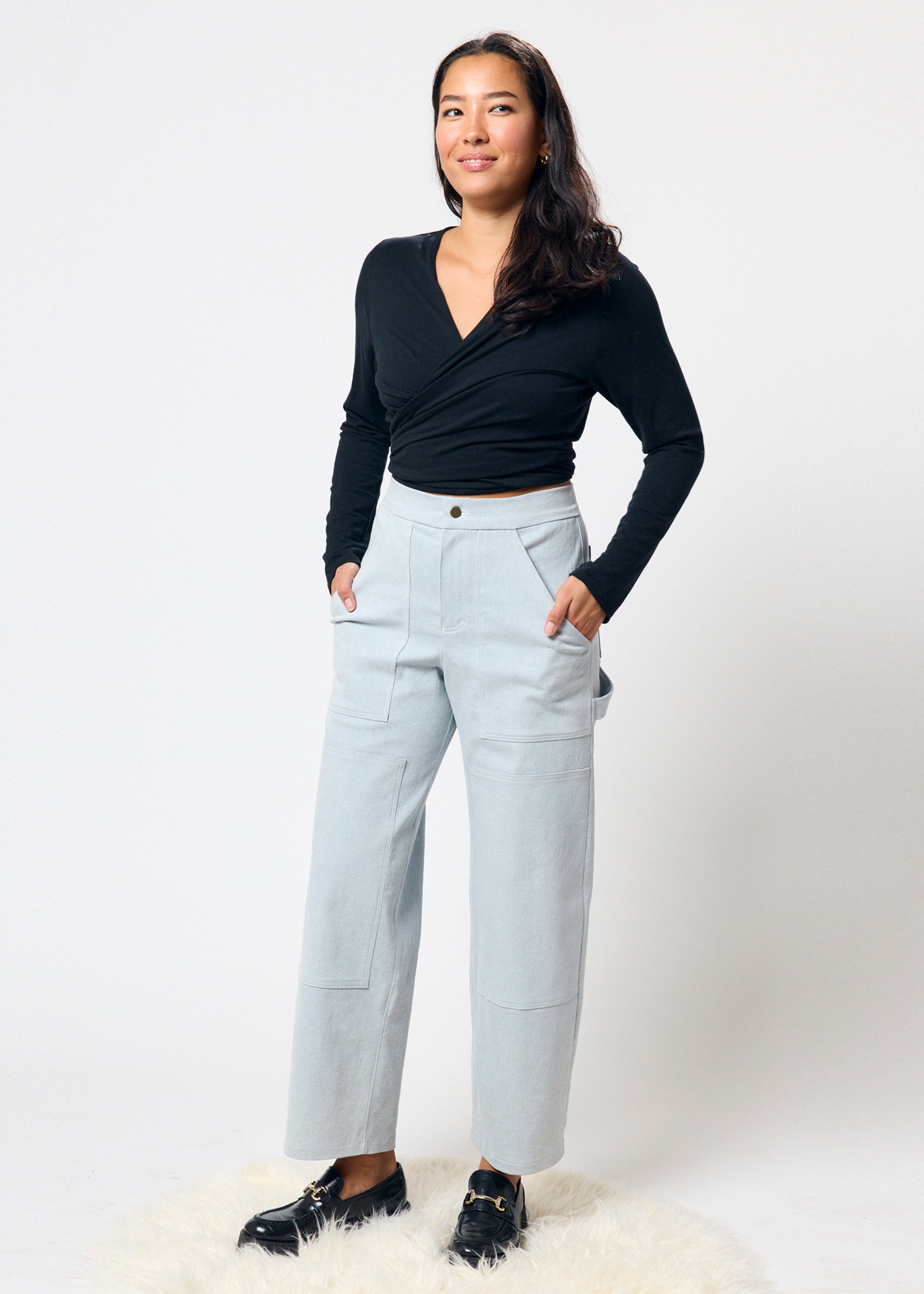 Woman wearing a black top and light gray pants on a white background