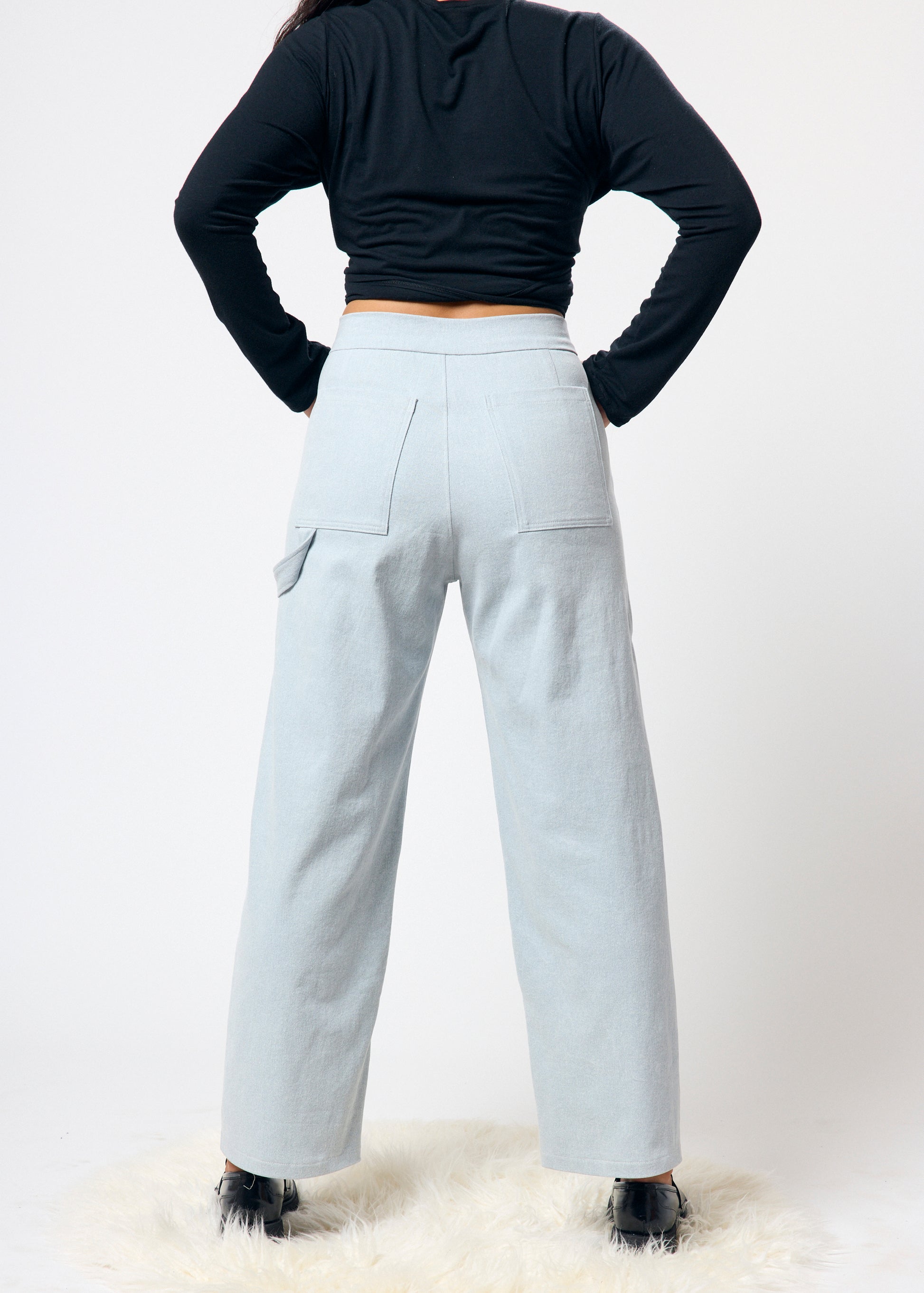 Person wearing light blue cargo pants and a black top on a white background