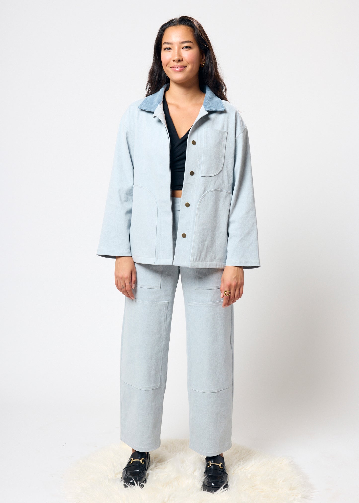 Woman wearing a light blue jacket and pants on a white background