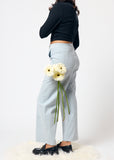 Person wearing light blue jeans holding white flowers on a white background
