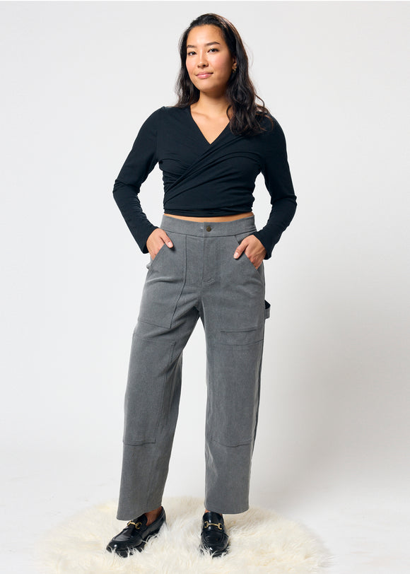 Woman wearing a black top and gray pants on a white background