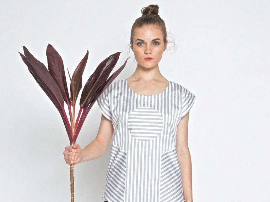Woman holding a large leafy plant against a plain background