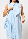 Woman wearing a light blue and white striped dress with ruffled layers on a plain background