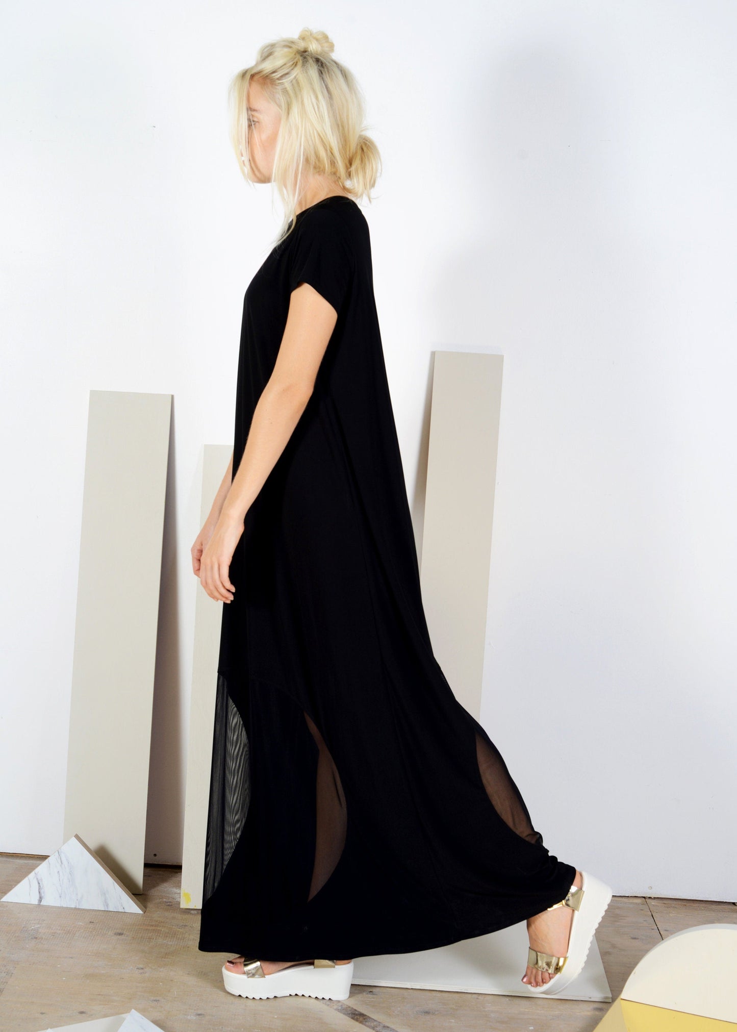 Woman wearing a black dress with cut-out sides in a minimalistic setting