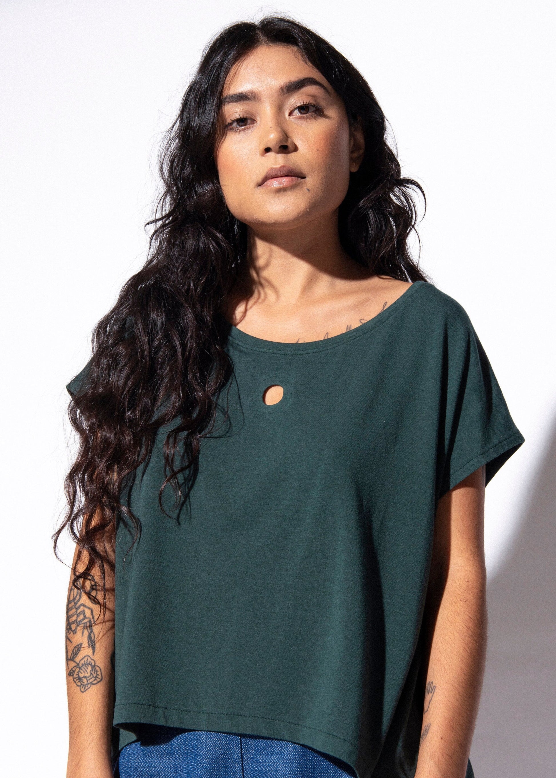 Woman wearing a green top and blue jeans against a white background