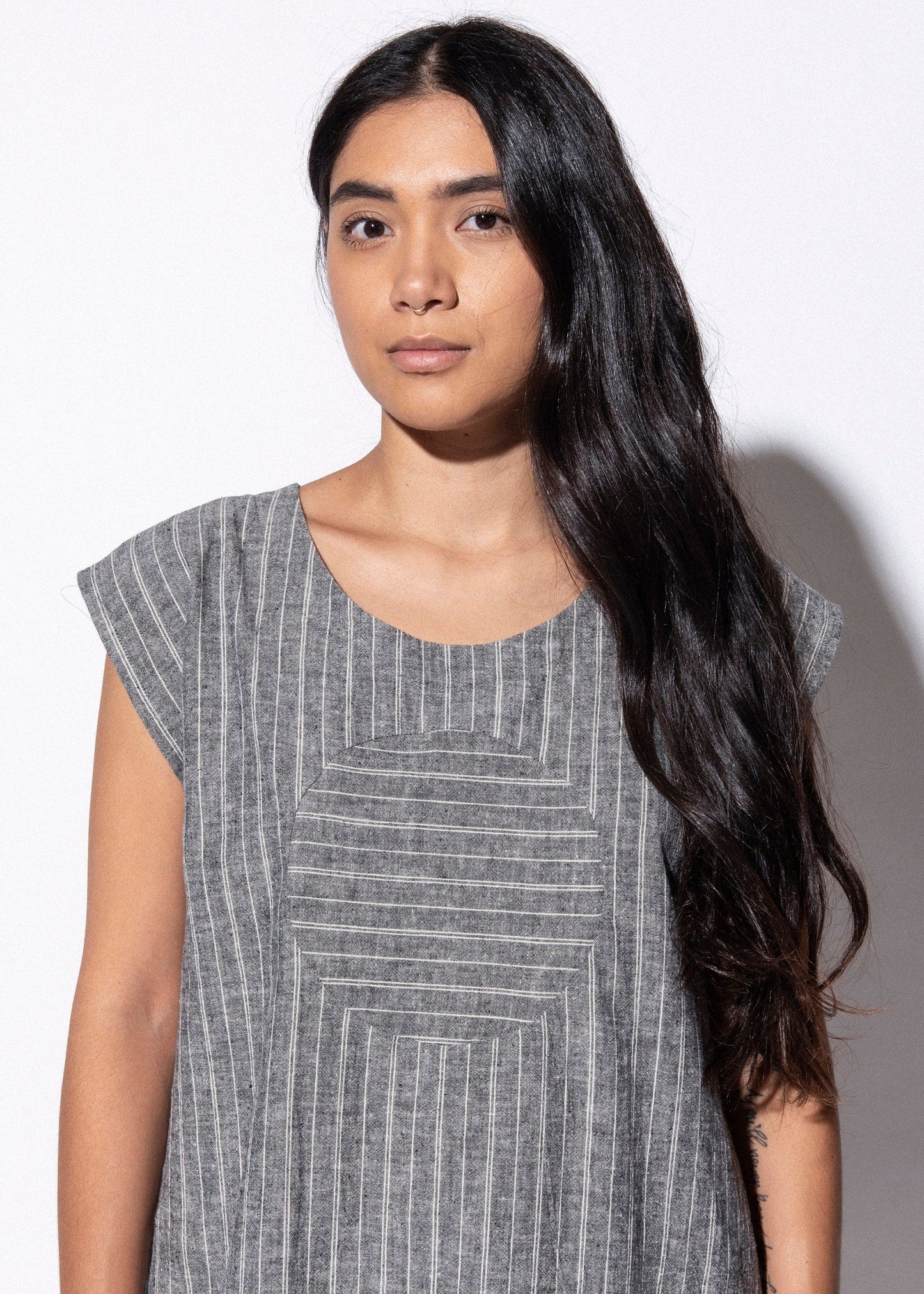 Woman wearing a gray patterned dress against a white background
