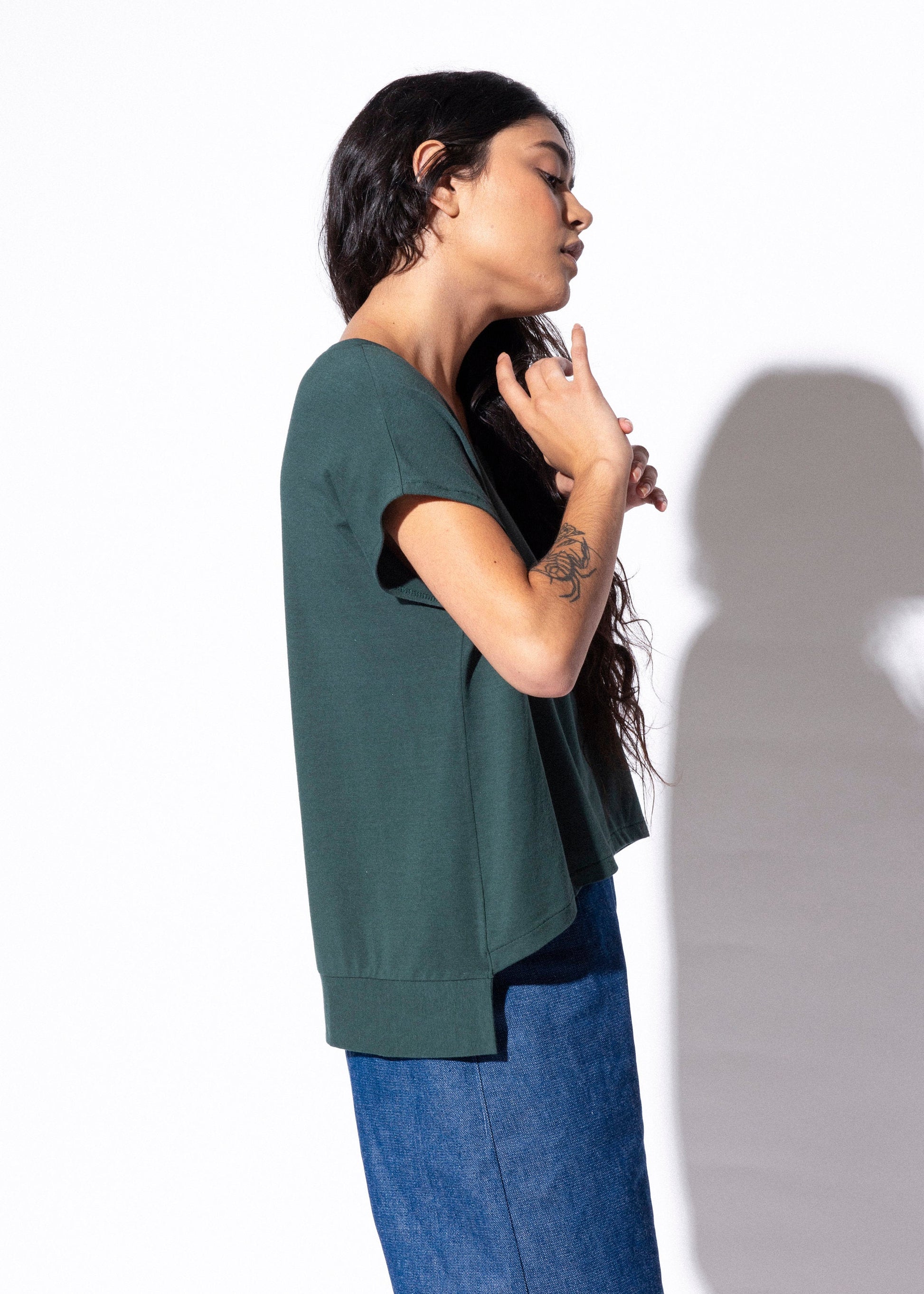Person wearing a green shirt and blue jeans against a white background
