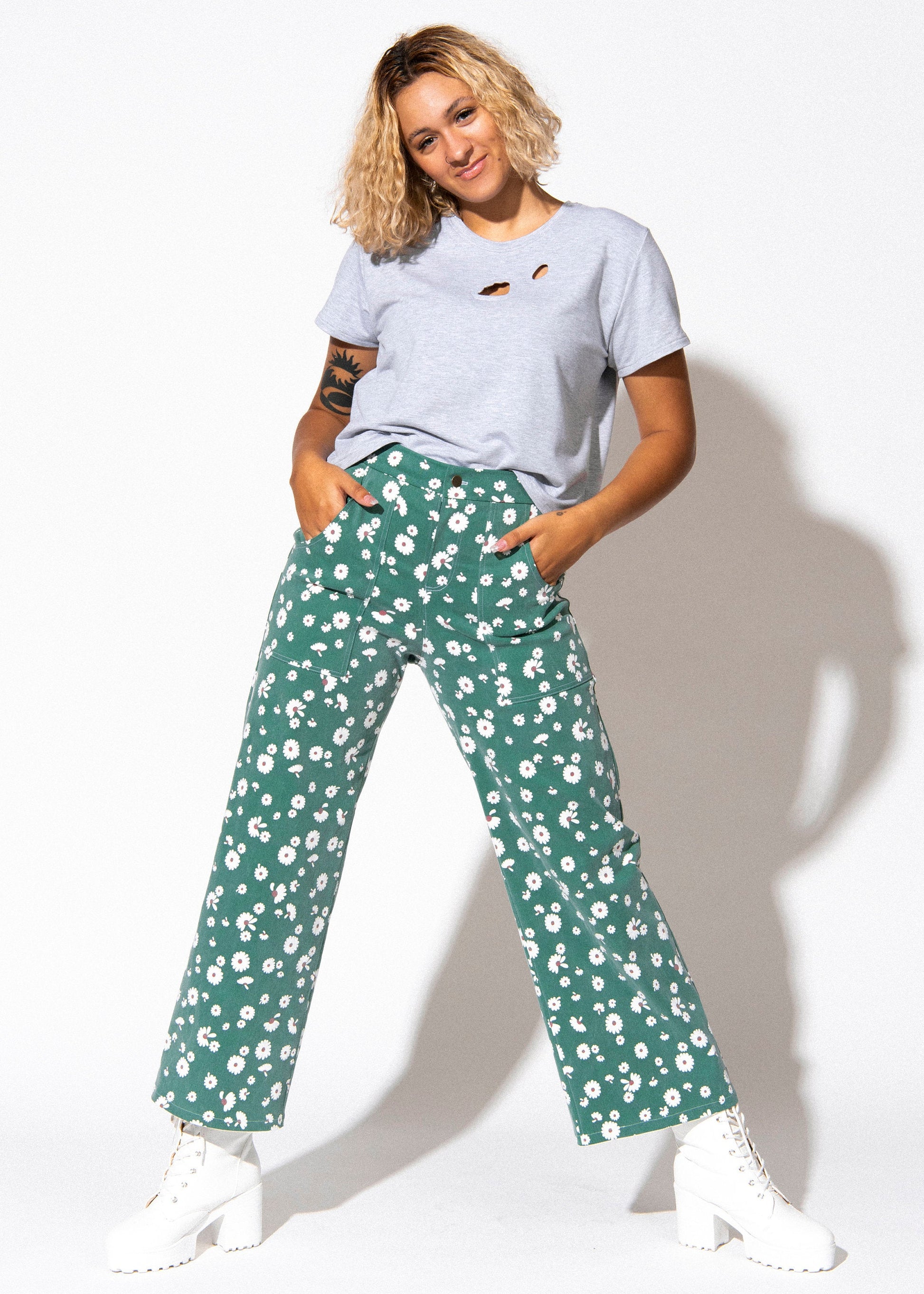 Woman wearing a white t-shirt and green floral pants on a white background