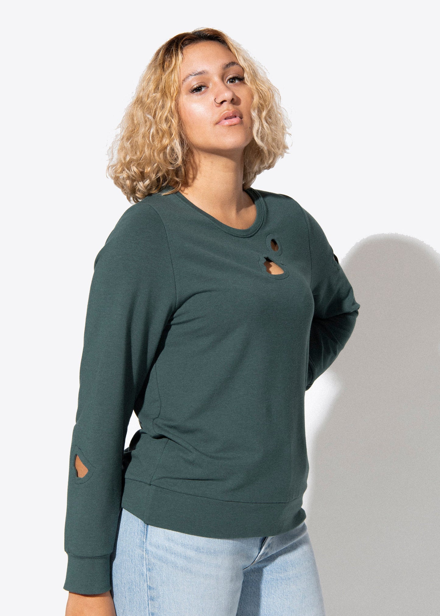 Woman wearing a green sweatshirt with distressed details on a white background