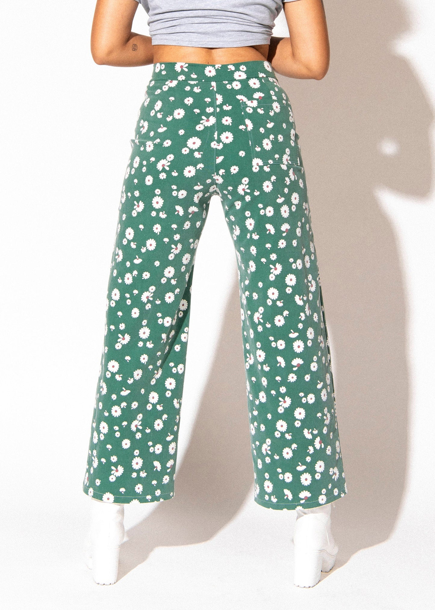 Green floral pants worn by a person on a white background