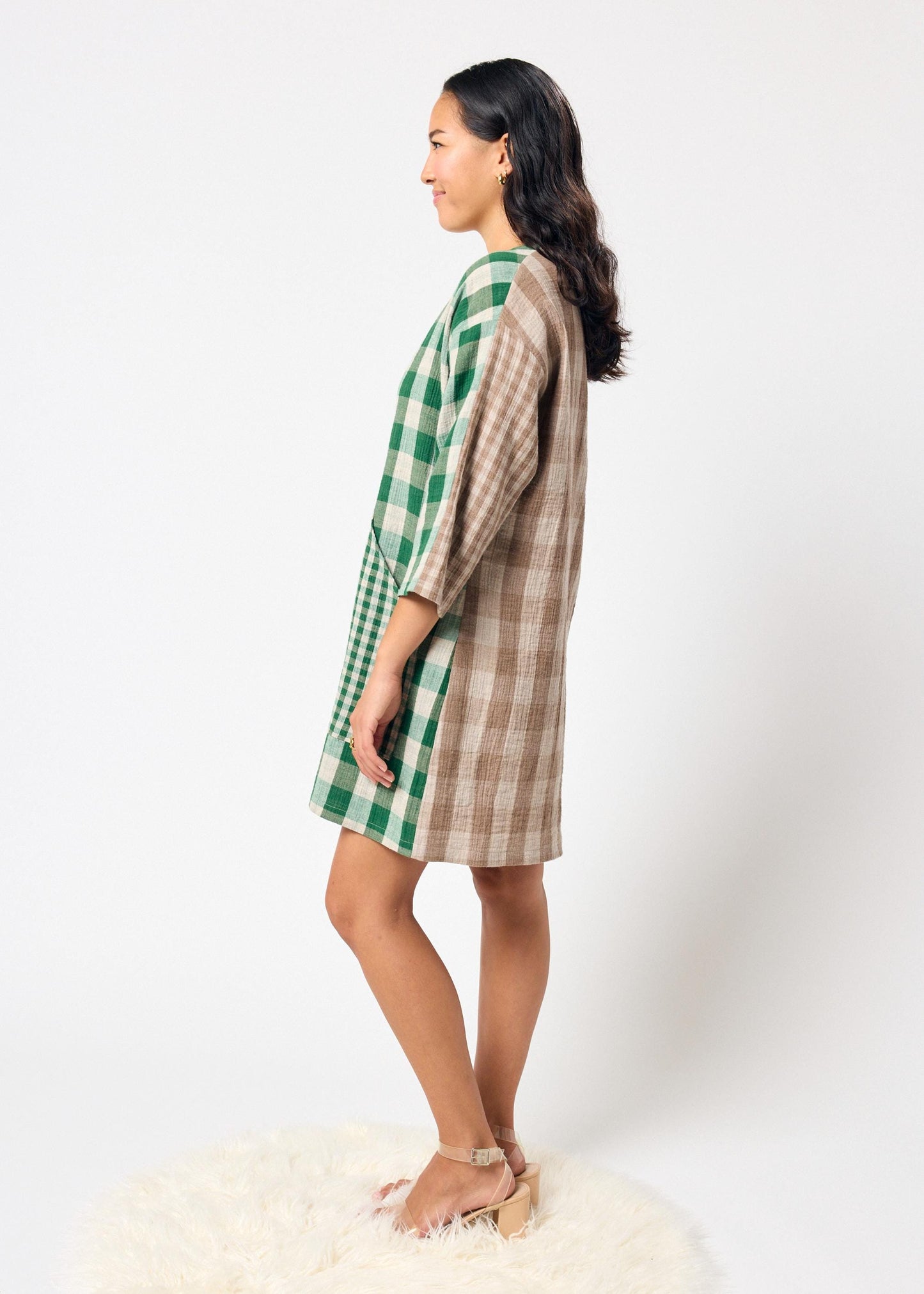 Woman wearing a green and brown checkered dress on a white background