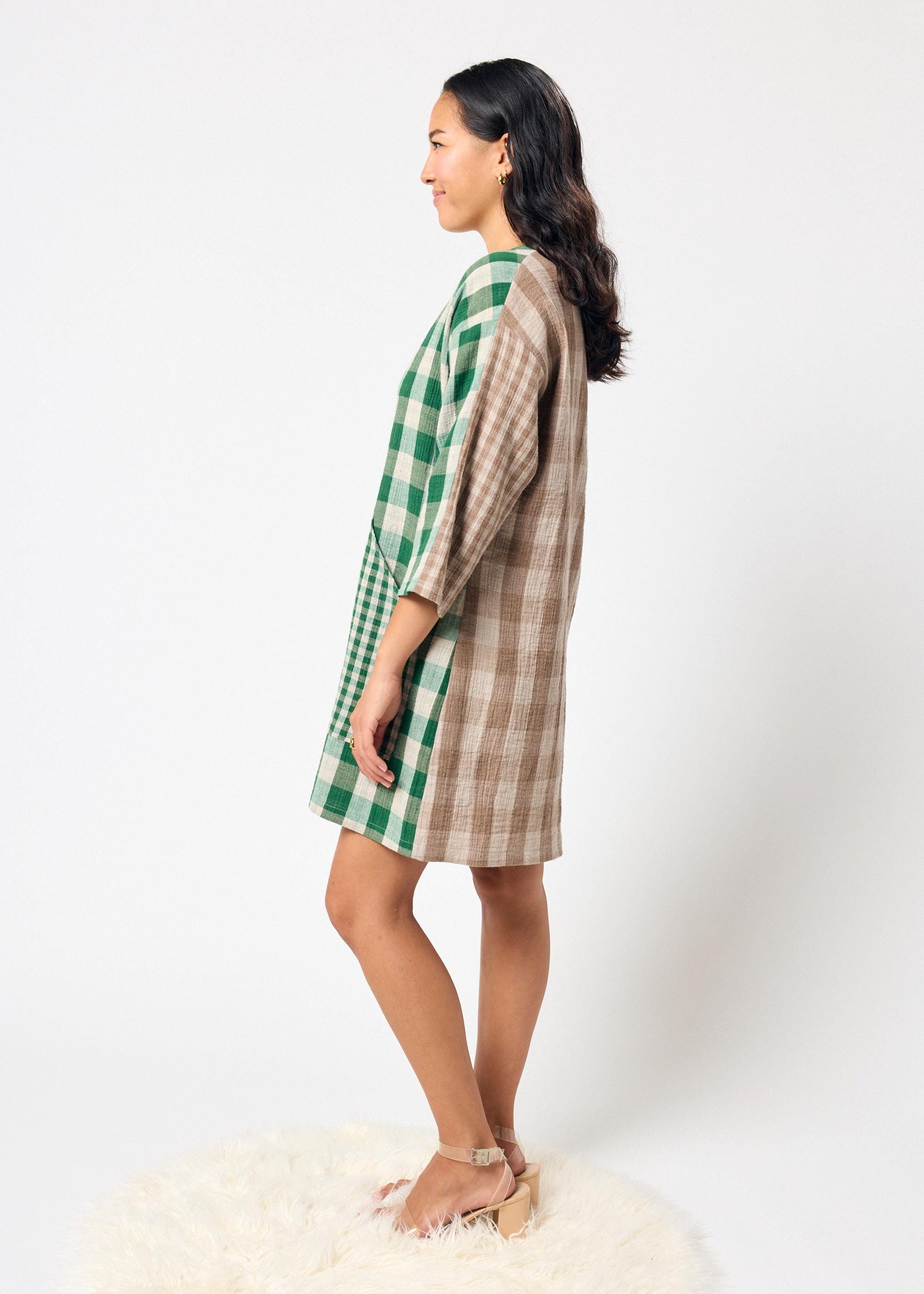 Woman wearing a green and brown checkered dress on a white background