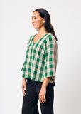 Woman wearing a green and white checkered shirt against a white background