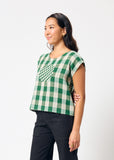 Woman wearing a green and white checkered top against a white background