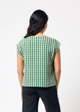 Person wearing a green and white checkered top on a white background